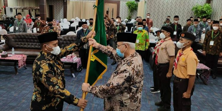 Ketum DPP LDII KH Chriswanto Santoso menyerahkan pataka simbolis kepada Ketua Terpilih LDII Maluku Utara, Nurhadi. Foto: LINES.