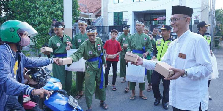 Pengurus PC LDII Kecamatan Gunung Anyar membagikan takjil kepada para pengendara yang melintas di kawasan Middle East Ring Road (MERR), Surabaya, Jawa Timur. Foto: LINES.