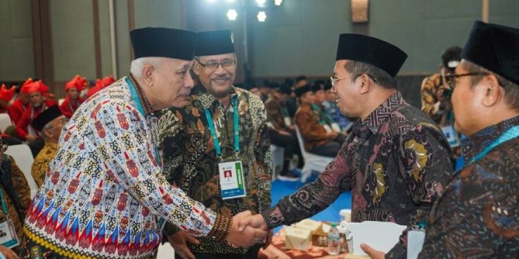 Direktur Penerangan Agama Islam Muchlis M Hanafi bersalaman dengan Ketua DPP LDII KH Chriswanto Santoso pada Munas X LDII. Foto: LINES.