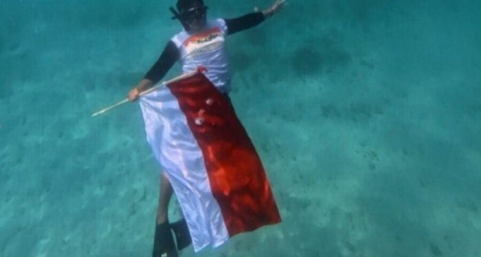 Pemuda LDII Bali mengibarkan bendera bawah laut di Laut Padang Bai. Foto: LINES.