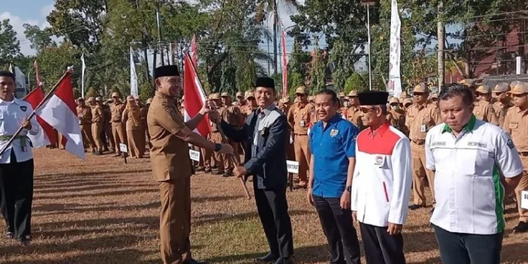 Bupati Tanah Laut Rahmat Trianto menyerahkan bendera secara simbolis kepada perwakilan ormas, tokoh agama, dan berbagai instansi. Foto: LINES